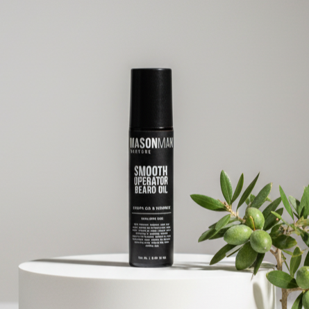 Mason & Main beard oil bottle on a white pedestal with a plant in the background