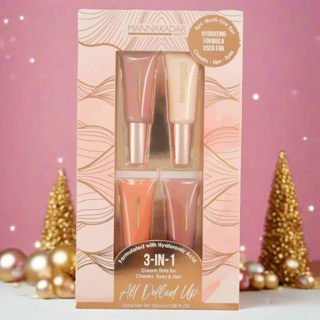 Manna Kadar All Dolled Up 4pc set in pink and gold foil wavy design box on pink background with gold christmas decor